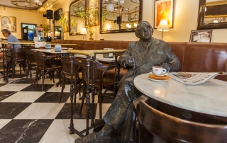 Imagen frontal de la estatua de Torrente Ballester en el Café Novelty